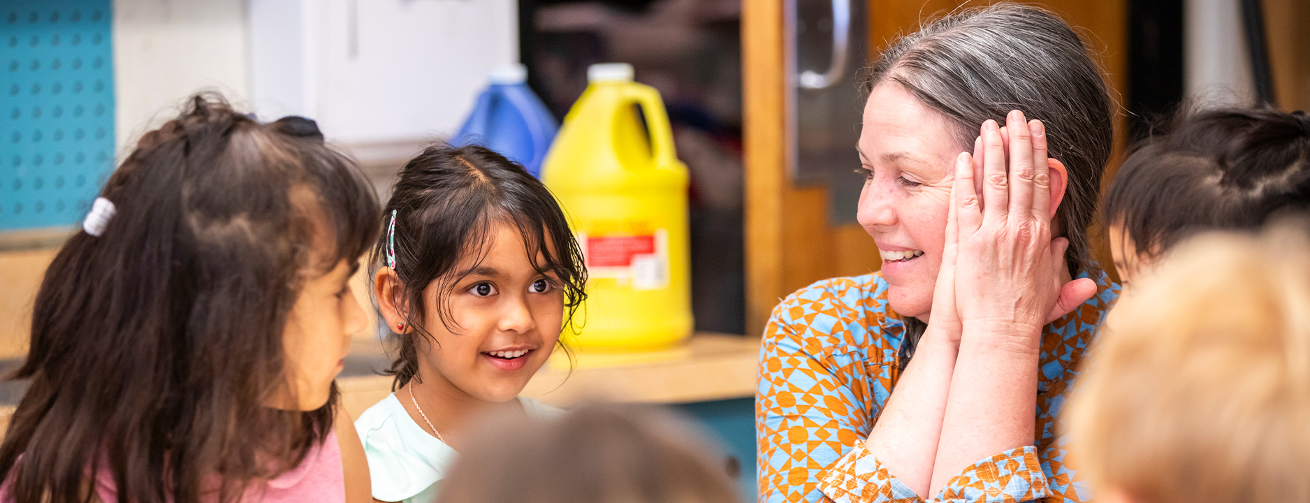 A teacher working with young students in a classroom