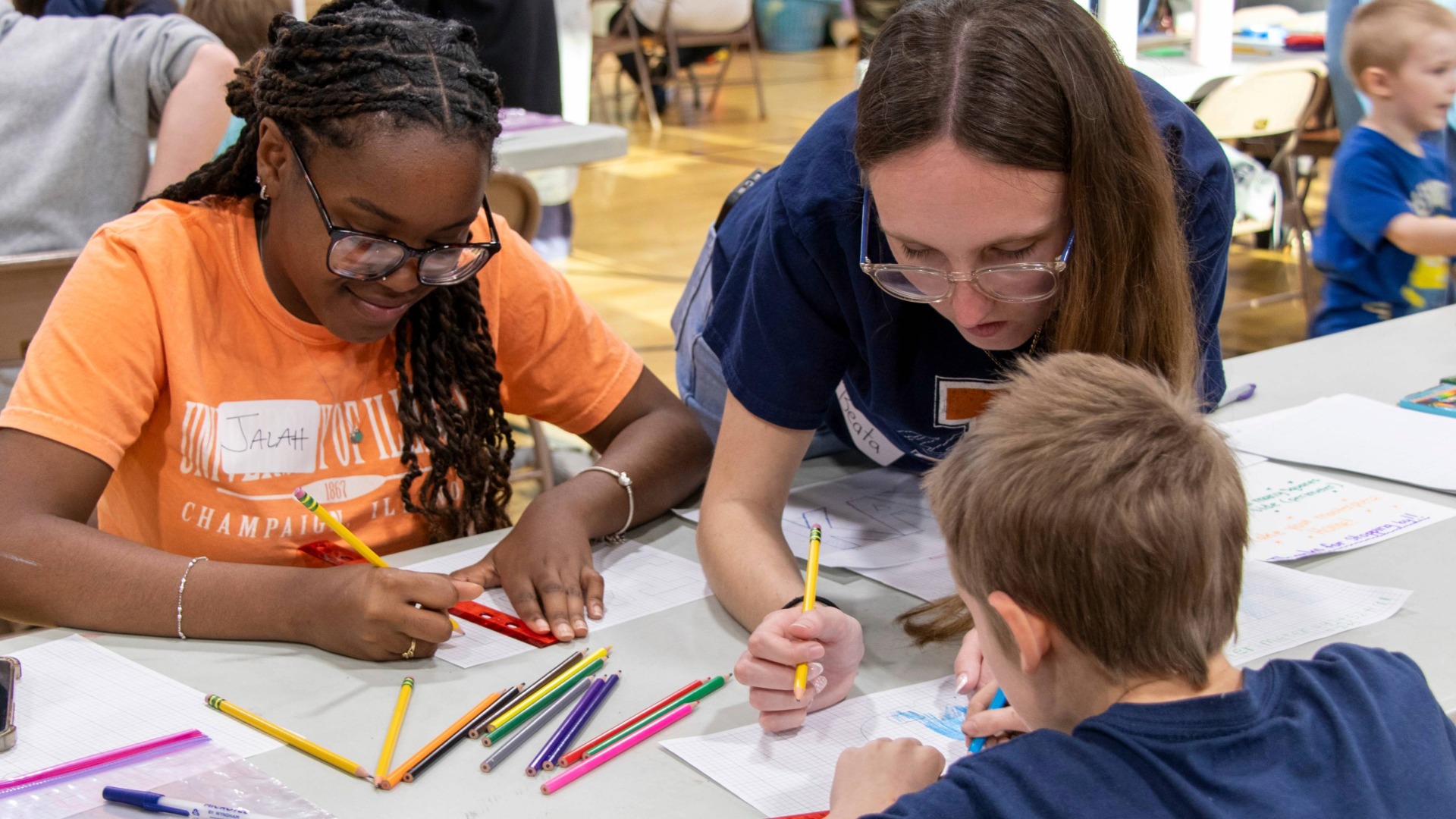 two student-teachers working with a student on an activity